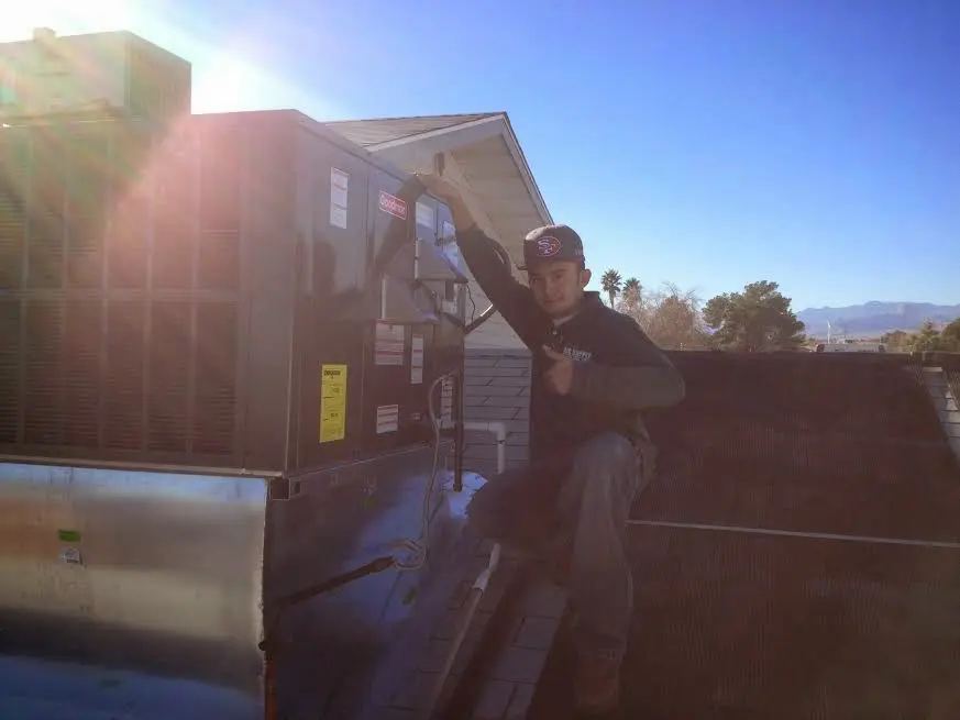 HVAC technician performing Air Duct Repair on a rooftop unit in West Clarkston-Highland